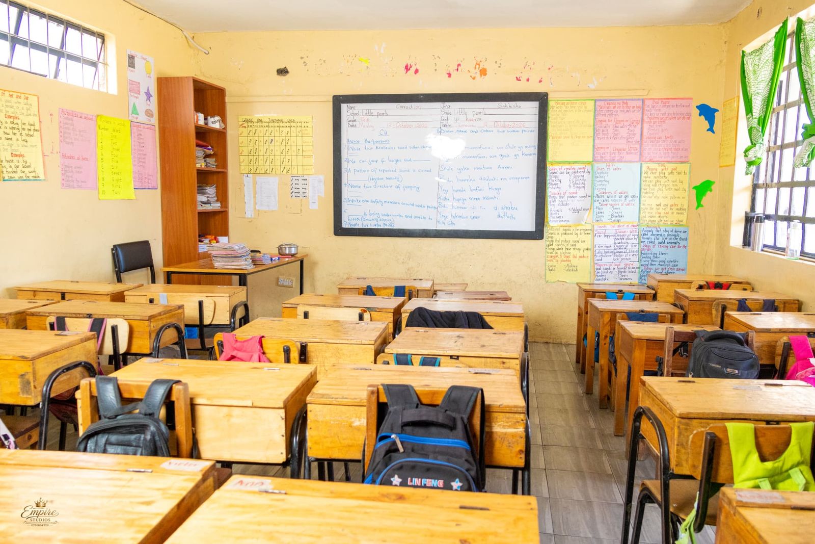 The Grade One classroom with wooden desks, the day's lesson on the whiteboard and learning charts